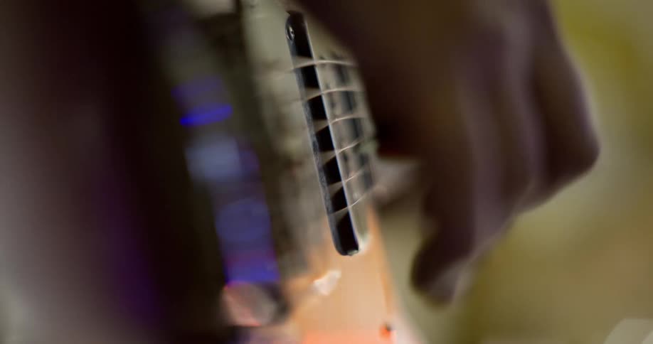 Close up of a hand plucking stings of an electric guitar with a plectrum