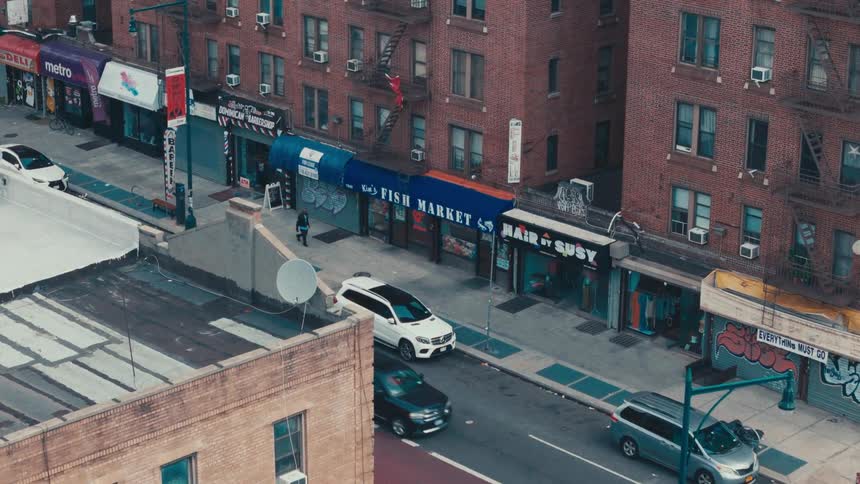An aerial view of a city street with a row of brick buildings lining the street
