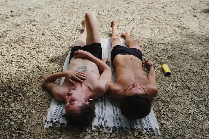 Two young men sunbathe outdoors