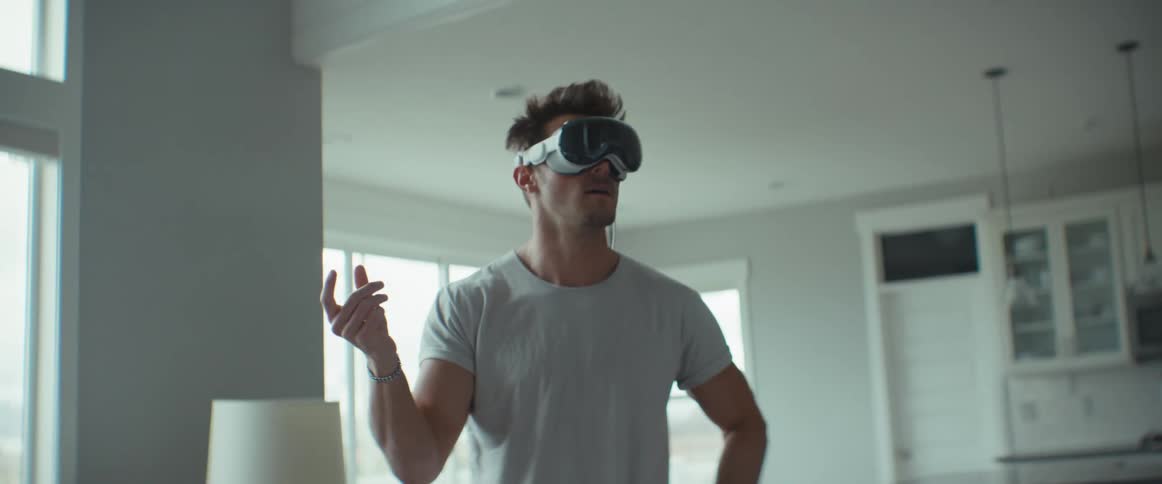 Man standing in home gestures while interfacing via virtual reality headset