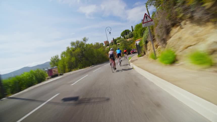 Four cyclists speeding down a rural road