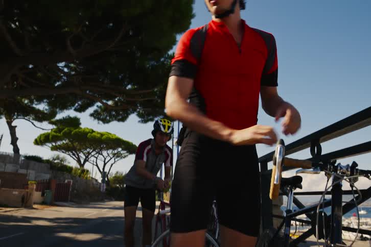 Two men riding bicycles park their bikes on the side of the road and start walking