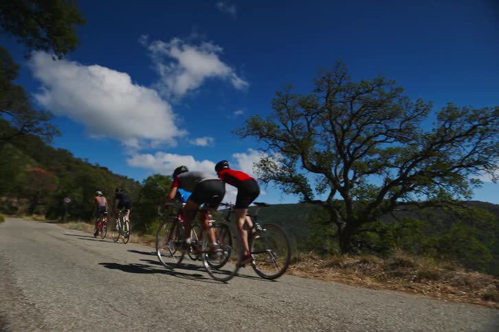 Group of men cycling on a narrow road in natural environment