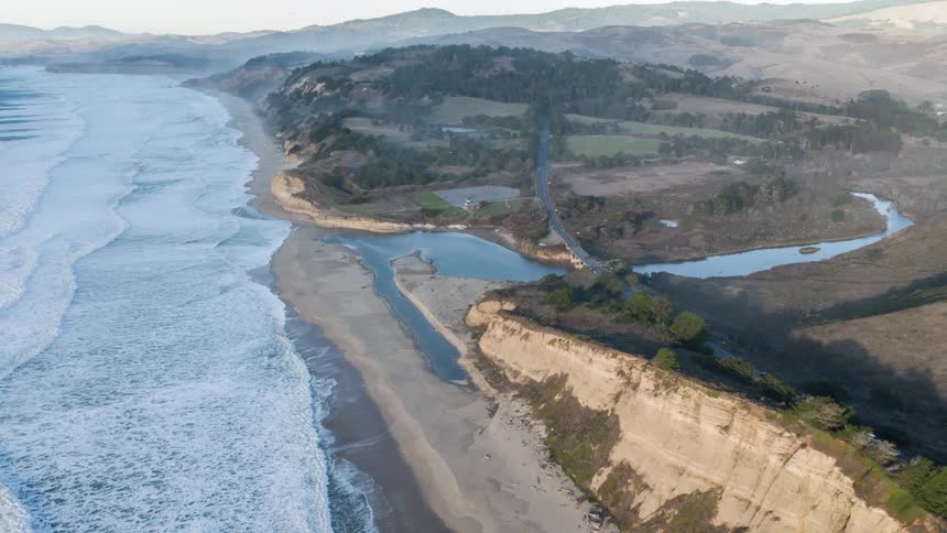 Aerial view of a river flowing into the sea across a beach