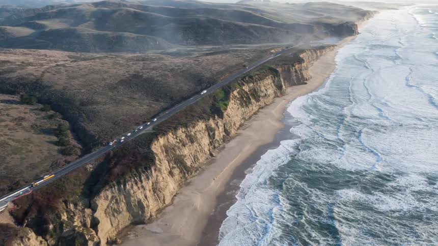 Aerial of sea waves gently rolling on a sandy shoreline along the coast