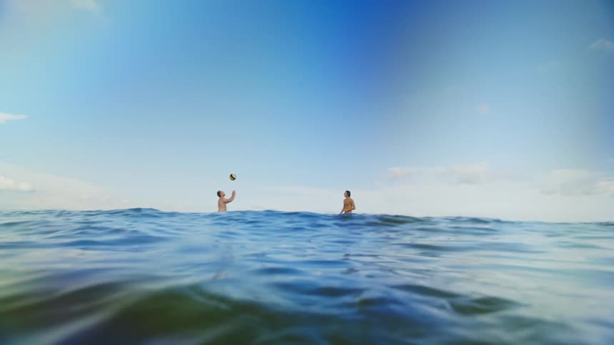 Two friends are playing volleyball in the water