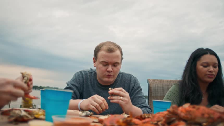A group of people eat seafood on a shoreline
