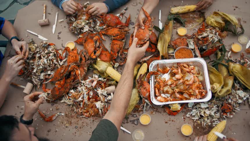 Group of people sitting at a table peeling crabs