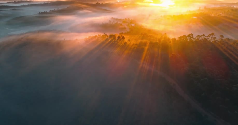 Aerial panorama of a mountain with forest and fog and the reddish sun reflection of the morning sky