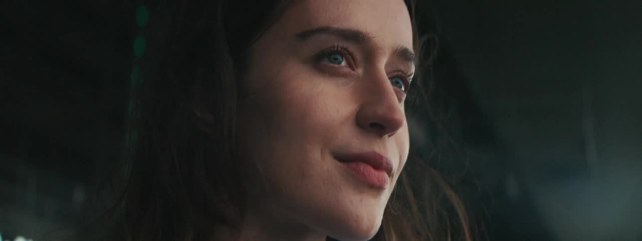 Woman standing outside under a building overhang on a windy day smiles