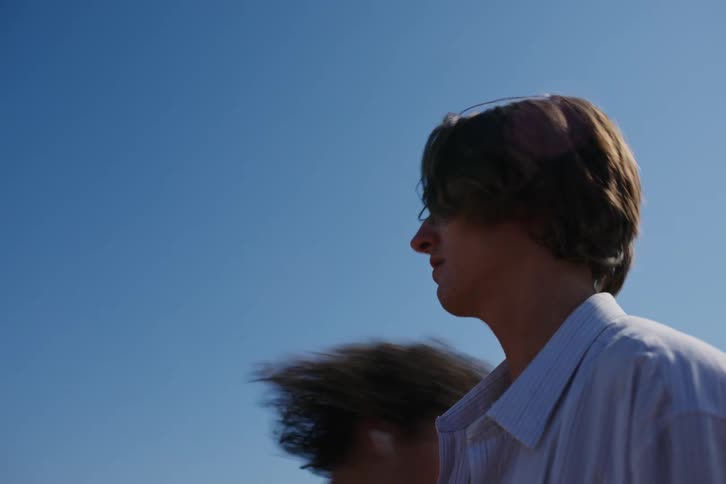 Portrait of two young people holding hands on the sand by the sea looking romantically and then other people arrive