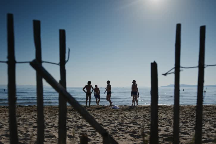 Five boys are playing in the sea when they run to the sand