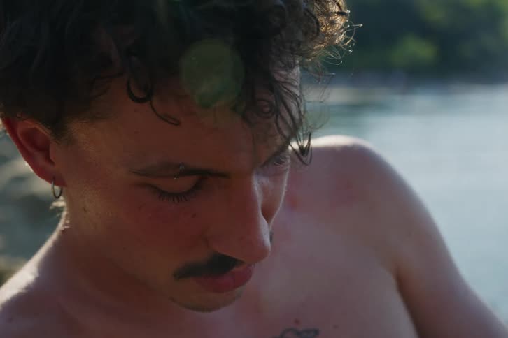 Portrait of a shirtless young man with a concentrated facial expression by the sea