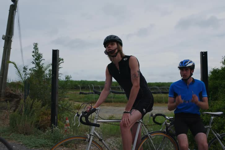 Three men on bicycles discuss their route before leaving the area