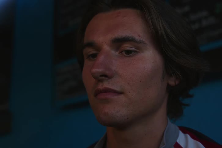 A young man drinks indoors