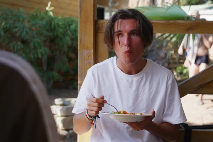 A man eating outside with another man