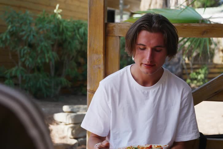 A man is eating spaghetti outside