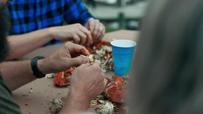 People sitting around a table are pulling apart crab shells by hand