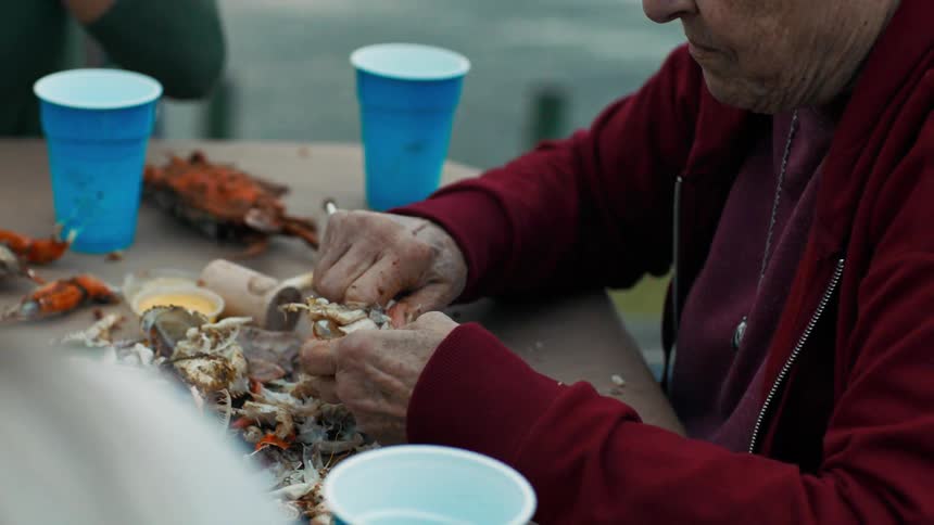 Three people sit at an outdoor table eating
