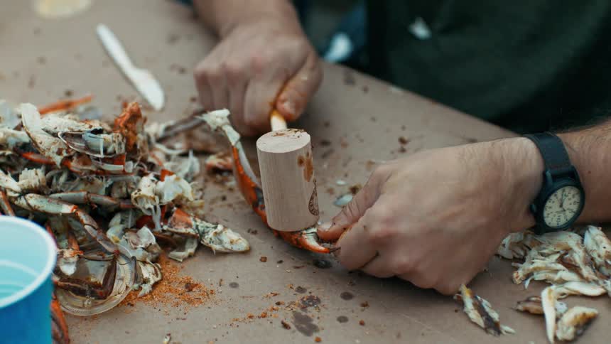 Man hitting a crab leg with a mallet