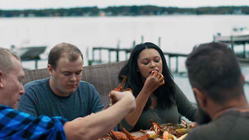 People sitting at a table next to the sea and eating crab