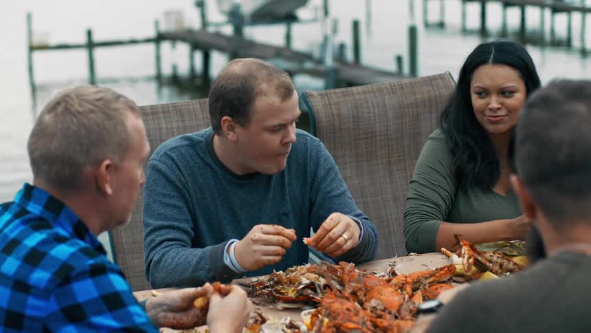 Group of people sitting at a table by the sea eating crab