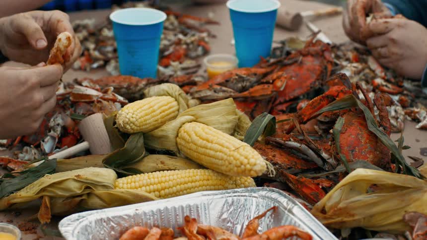Two people are sitting at a table preparing shellfish