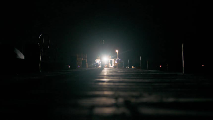 Man walking down a street at night with the reflection of lighting behind him