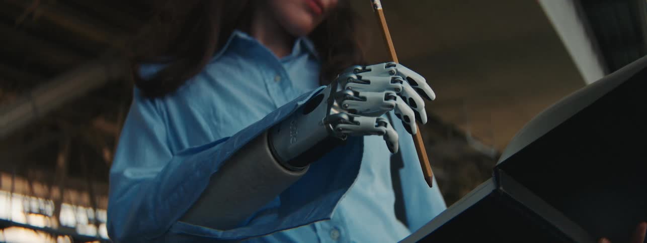 A woman with a robotic arm using a pencil