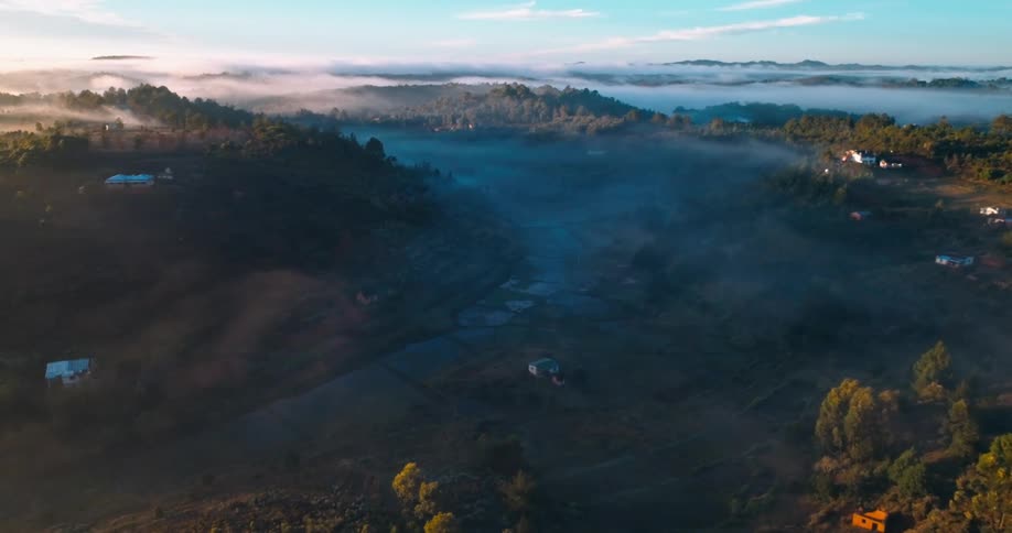 Aerial panorama of hills and mountains with some rural houses on a foggy morning