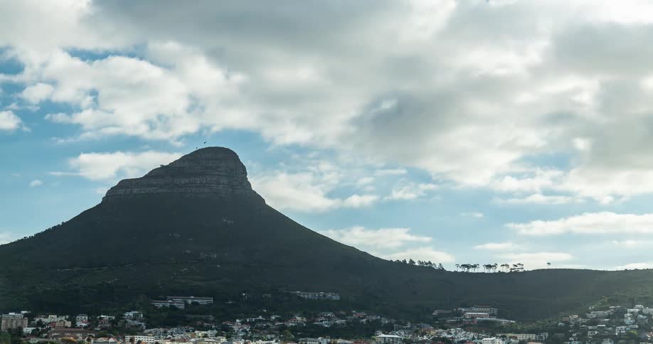 Time lapse of clouds moving over a city next to the mountains