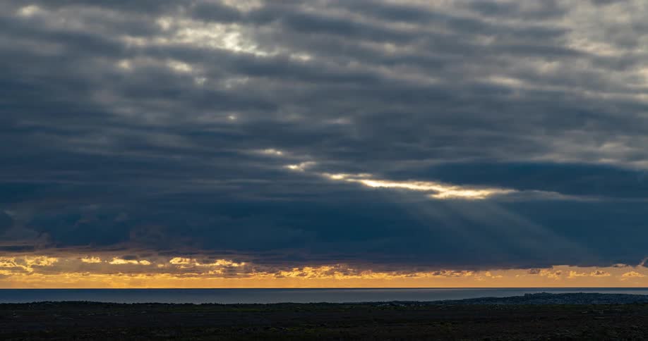 Time lapse of sunlight shining through patchy clouds over a blue ocean