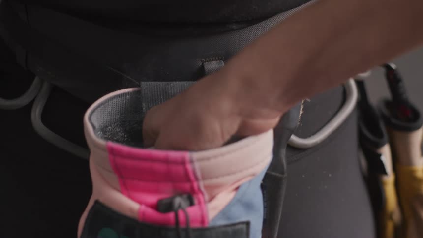 A person reaches into a cylindrical bag ties to a belt