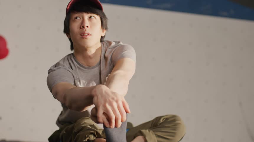 A young man in a red cap is sitting on the floor and stretching his foot