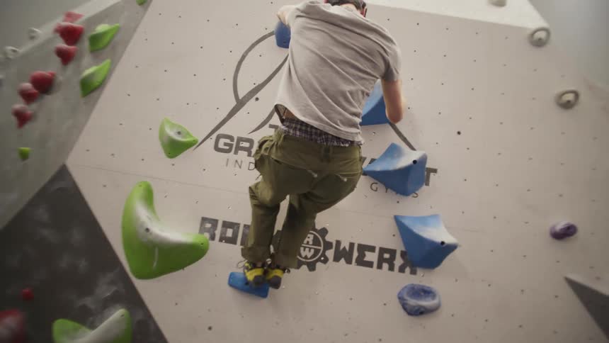 An asian man climbing in a gym