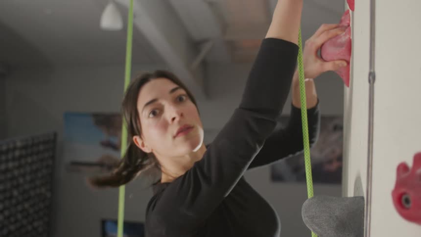 A woman climbs an indoor climbing gym
