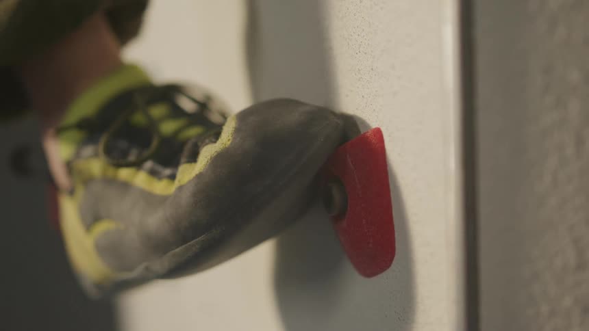 The foot of a person using a hold on the wall as support to climb