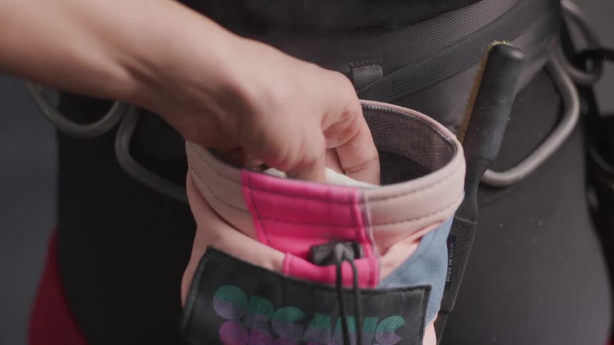 A person reaches their hand into a chalk bag used for climbing