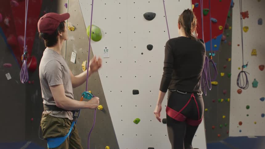 A man talks with a woman prior to her climbing up a rock climbing wall