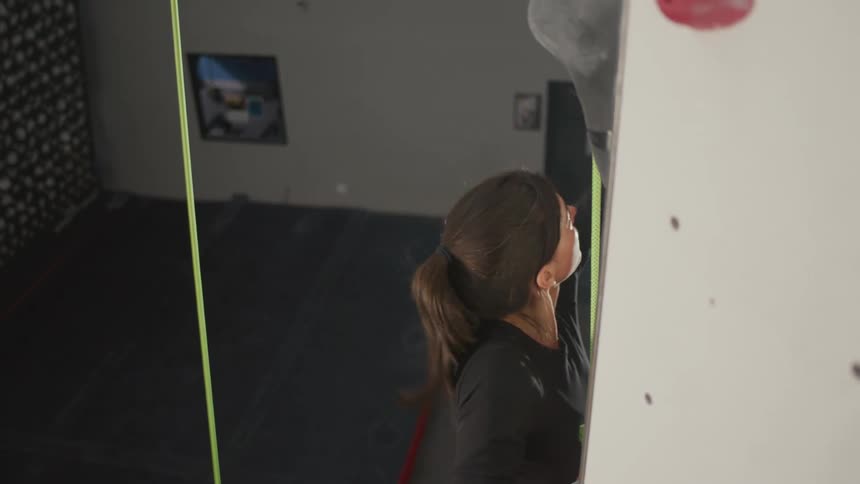 Woman with harness climbing a fake mountaineering wall