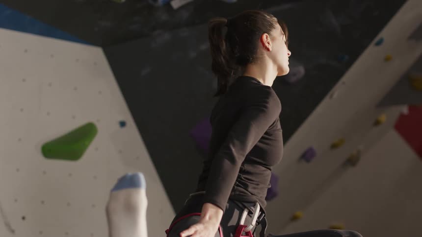 A woman stretches in a climbing gym