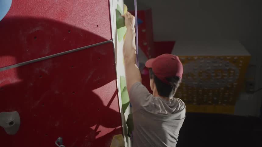Man climbing a fake mountaineering wall with a safety harness