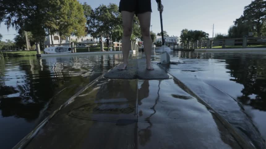 A person balances and paddles on a paddle board on a lake