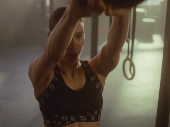 Woman working out with a kettle bell indoors in a gym