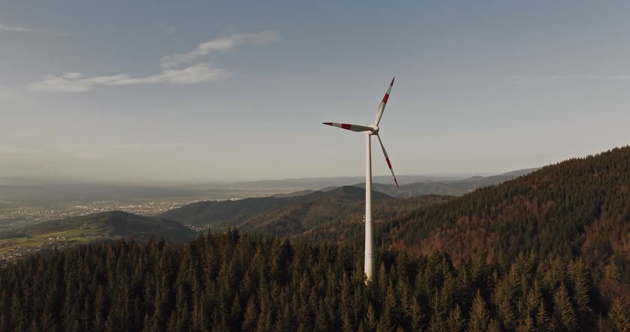 An aerial view of a large power generating windmill in a forest