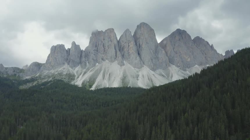 Landscape of a coniferous forest with mountains and rocky cliffs in the background on a cloudy day