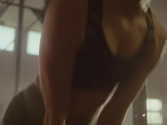 Woman in the gym lifting weights while her body contracts and expands