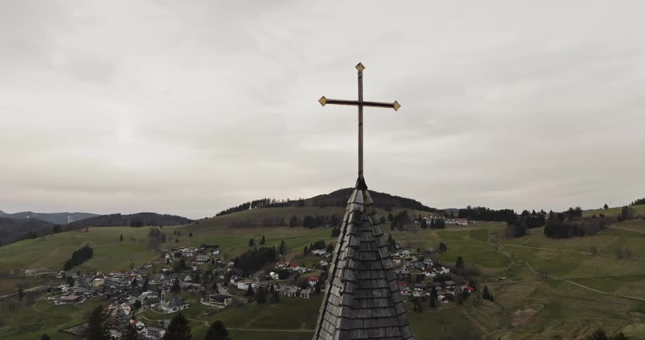 In a rural town the steeple of a church stands tall with a cross atop it