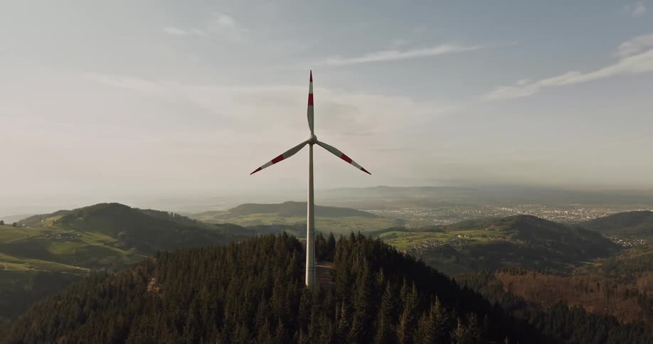 Aerial panorama of a moving wind power engine tower on a mountain peak