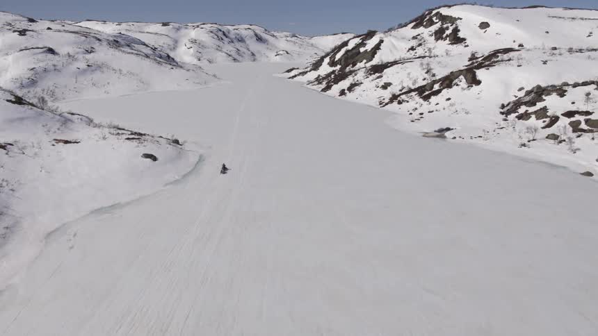 A person travels up a snowcovered mountain slope on a snowmobile